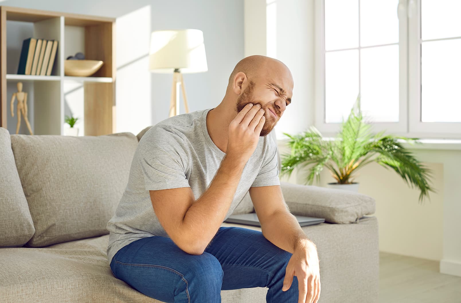 male with jaw pain holding his mouth while scheduling emergency dental appointment at the smile studio